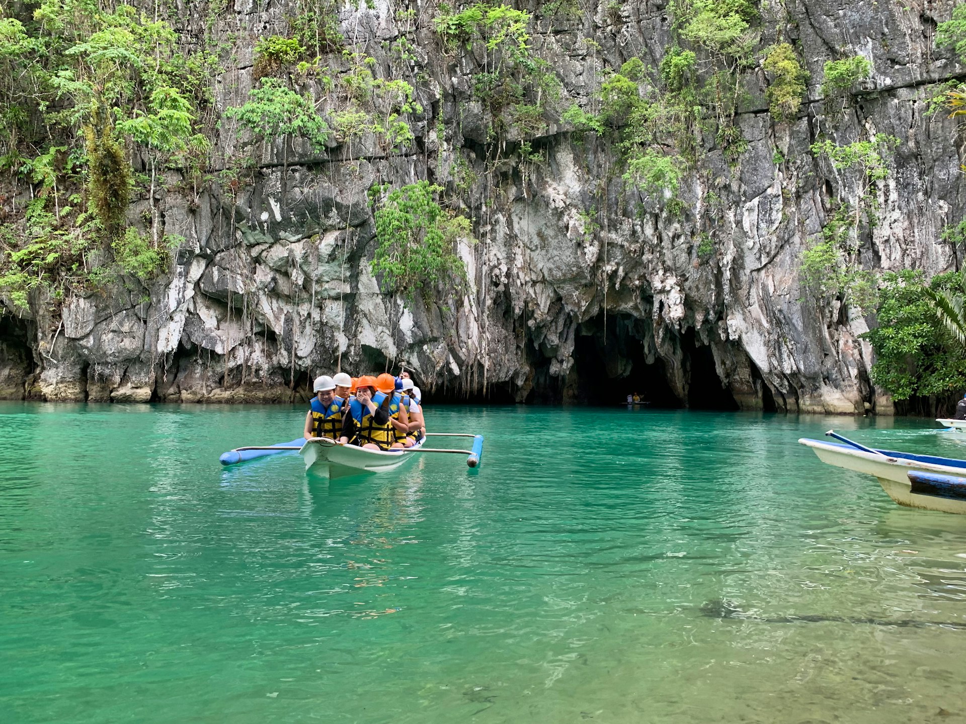 Bateau de visiteurs à l'entrée de la rivière souterraine de Puerto Princesa, falaise calcaire et eau verte