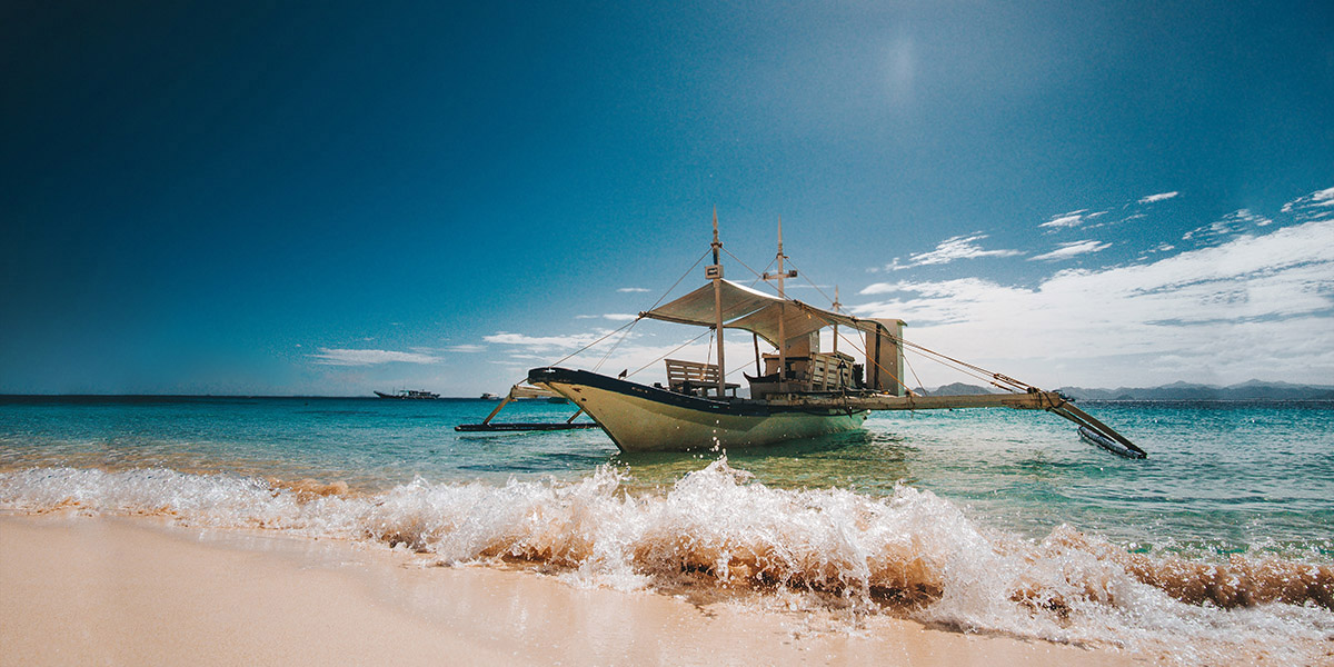 Bangka traditionnel sur l'eau turquoise près du rivage