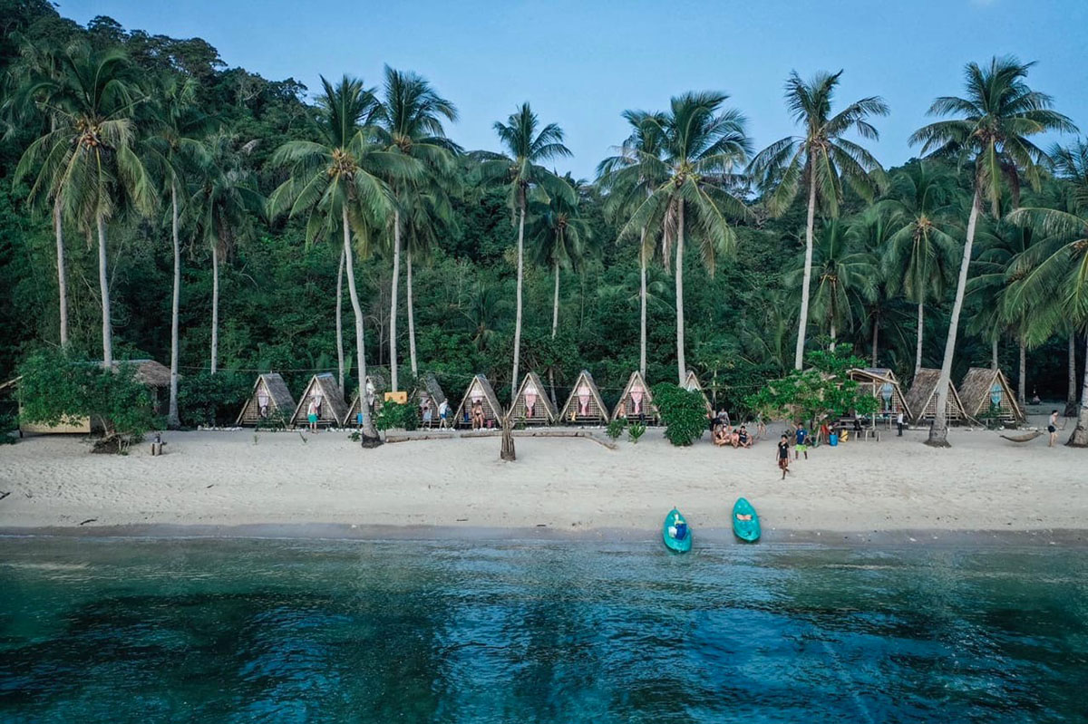 Campement de huttes sur une plage d'île, vue drone