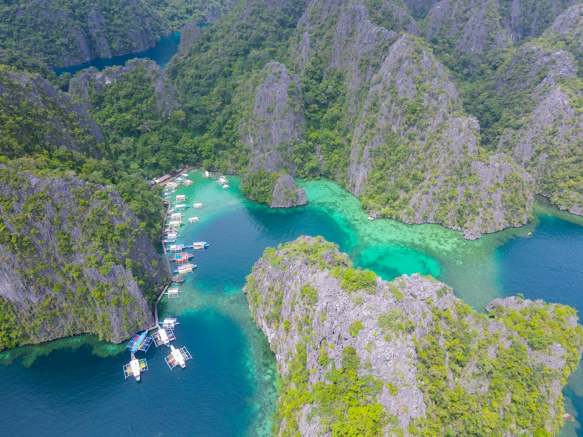Bateaux amarrés dans un lagon turquoise entouré de falaises calcaires, Coron