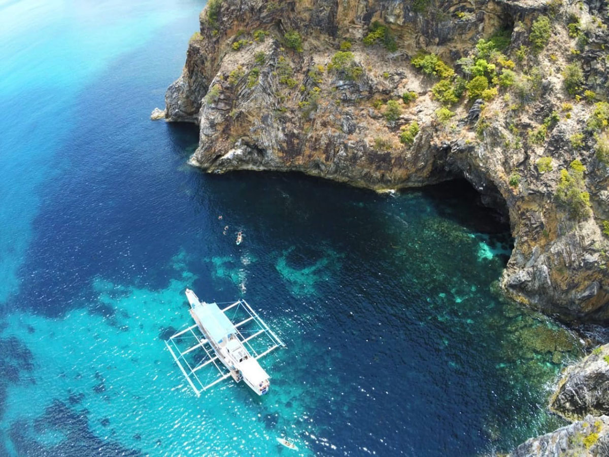 Bangka au pied d'une falaise calcaire, eau turquoise, nord de Palawan