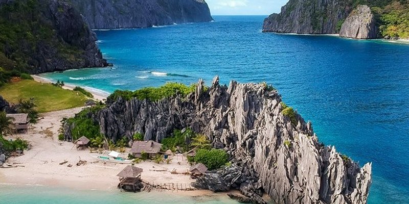 Vue aérienne de Matinloc, falaises calcaires et petite plage, El Nido